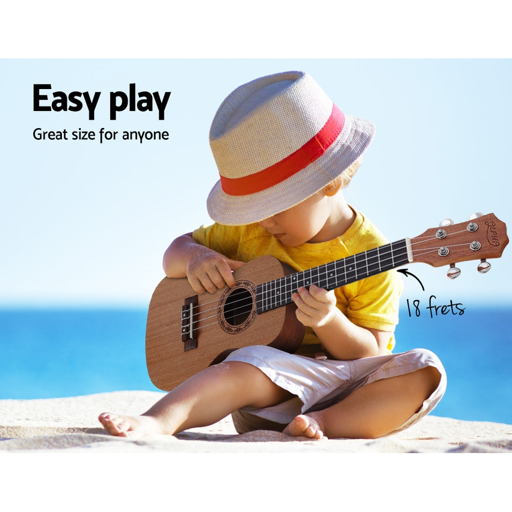 Child playing ukulele on beach. 18 frets.